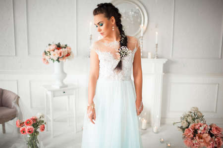 Delicate bride with flower in her hair stands in the room. The girls body painted with mehendi. Amid the candles, flowers beautiful interiorの写真素材