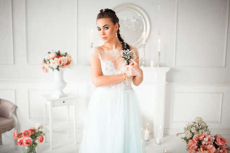 Delicate bride with flower in her hair stands in the room. The girls body painted with mehendi. Amid the candles, flowers beautiful interiorの写真素材
