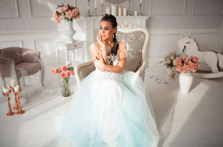 Bride with makeup and flower in her hair sitting on a chair. The girls body painted with mehendi. Amid the candles, flowers beautiful interiorの写真素材