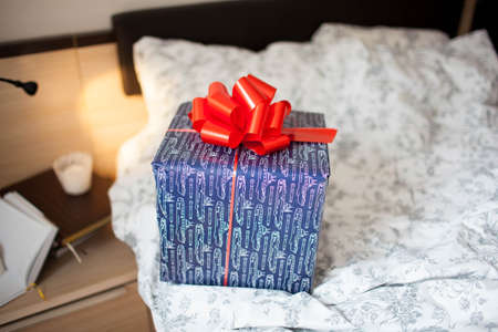 Blue gift box with a bow on the bed. Surprise.の写真素材
