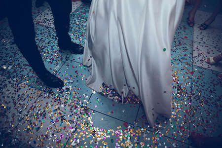feet of the bride and groom on a background of confettiの写真素材