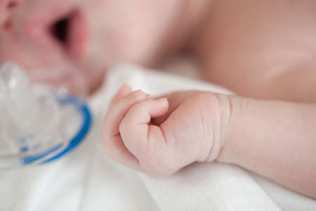 Hand the sleeping baby in the hand of mother close-up.