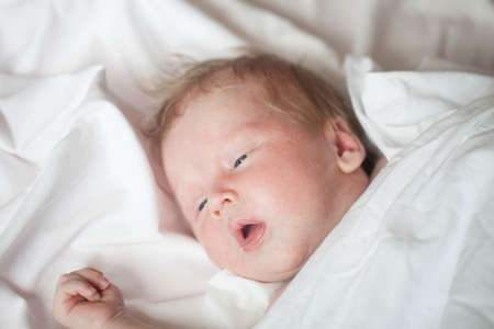 Peaceful baby lying on a bed while sleeping in a bright room