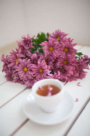 Female hands holding cups of coffee on rustic wooden backgroundの写真素材