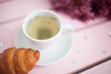 Female hands holding cups of coffee on rustic wooden backgroundの写真素材