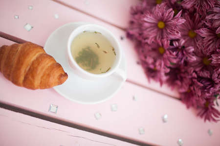 Female hands holding cups of coffee on rustic wooden backgroundの写真素材