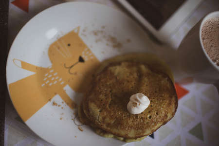 The baby eats pancakes with sour cream and cocoa. Close up.