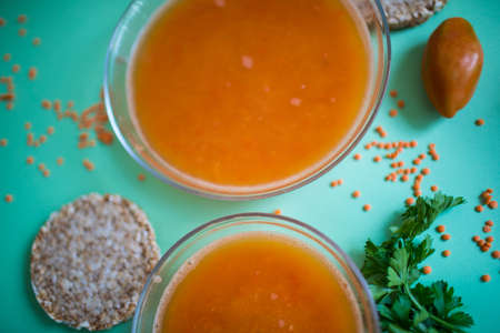 Spicy red lentil soup in a copper pot on a wooden table, close-upの写真素材