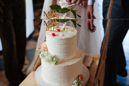 Multi-tiered white wedding cake with figures of the bride and groom. Close up
