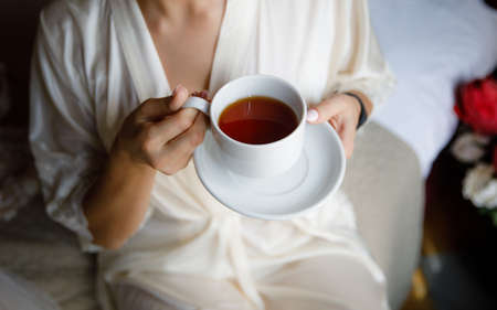 A young woman bride in a white coat holding a Cup of tea.の写真素材