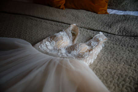 A beige wedding dress is lying on the bed in the room.の写真素材