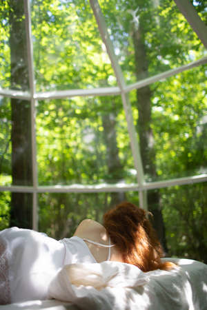 The girl woke up in the morning looking out the large panoramic window.の写真素材