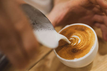 a cup of cappuccino coffee is being filled with cream. close up.の写真素材