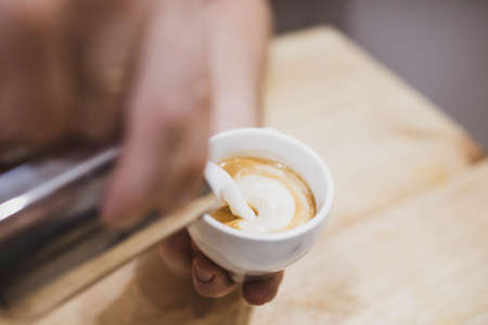 a cup of cappuccino coffee is being filled with cream. close up.の写真素材