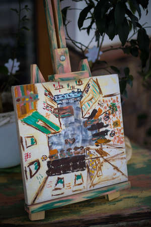 A small easel with a beautiful oil painting. On the street.の写真素材