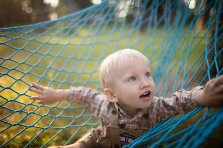 Three children having fun in a hammock in sunny weather.