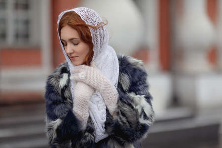 Russian red-haired girl in a white wool scarf in winter.の写真素材