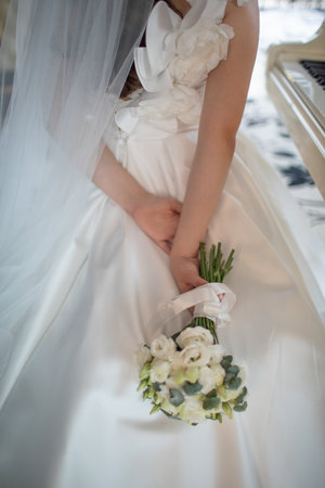 Bride holding bouquet of flowers in gorgeous white wedding dress and veil with no face showing.の写真素材