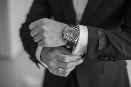Groom in suit, focused on watchの写真素材