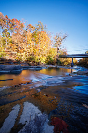 Autumn River Flowing Under Bridgeの写真素材