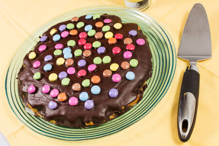chocolate cake with smarties on the yallow tableclothの写真素材