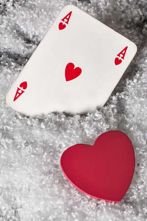 Red heart with ace of hearts in the snow