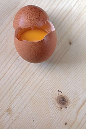 Open egg resting on a wooden baseの写真素材