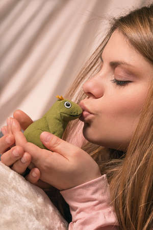 Girl kisses frog for it to become a princeの写真素材