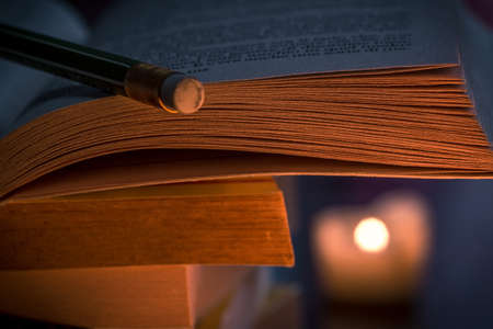 book and pencil in candle lightの写真素材