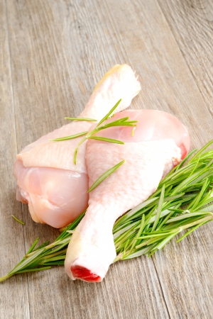 Raw chicken legs with rosemary on wooden tableの写真素材