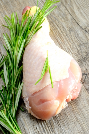 Raw chicken legs with rosemary on wooden tableの写真素材