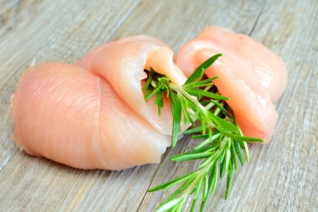 raw chicken breast sliced with rosemary on a typical wooden tableの写真素材