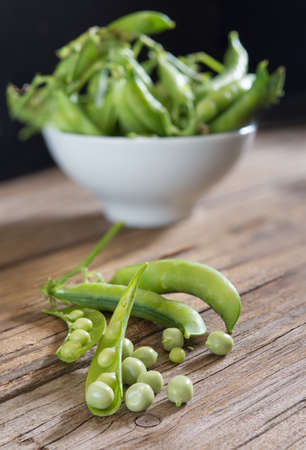 Fresh green peas on wooden table and black background