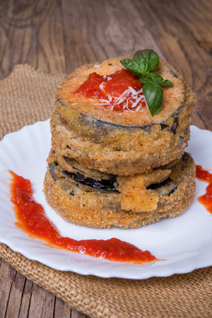 Round eggplant blanched with grated bread and fried bread stuffed with mozzarella with tomato sauce and parmesanの写真素材