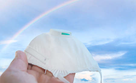 Medical antivirus mask FFP2 FFP3 in rainbow sky - concept to avoid virus and bacterial contagionの写真素材