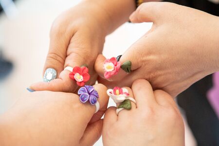 Four people, wearing flower rings, put their fingers together.の写真素材