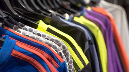 Customer or seller hand holding a hanger with clothes. Clothes on hangers on a shelf in the store, shop, supermarket. Products and service. Close up, selective focusの写真素材