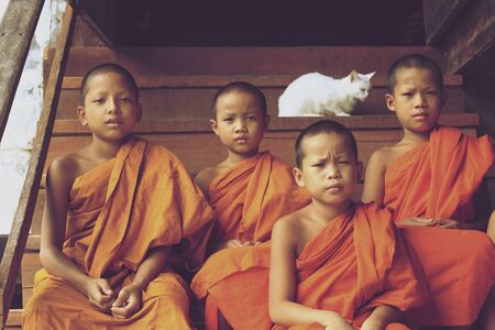 Mea Hong Son, Thailand-August 17, 2015: Novice monks sitting on stairs at wooden monk's houseの素材