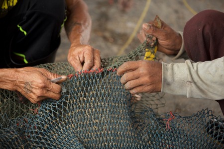 Selective focus on fisherman's hand, repairing fishing net