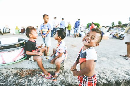 BALI, INDONESIA - AUGUST 13, 2016 : Cute smiling happy little boy while playing with his friends at fish market, Jimbaran, Baliのeditorial素材