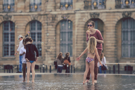 BORDEAUX, FRANCE - 3 september, 2016 : Woman blowing soap bubbles for kids to play with  in one of the hotest summer day at Bordeaux water mirrorのeditorial素材