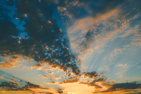 Cumulus sunset clouds with sun setting down and sun raysの写真素材