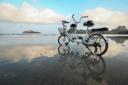 Tandem Bicycle on the beach with its reflection on the beach, grain texture style applyの写真素材