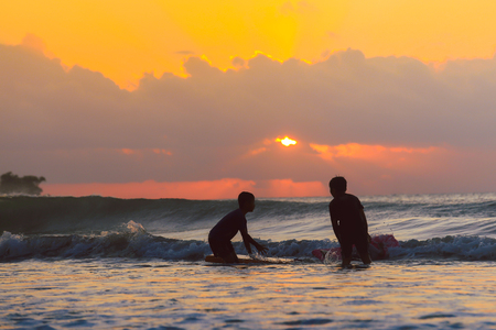 Golden sunset and group of kids enjoy playing on the beach with sun rays sky at Jimbaran beach,...