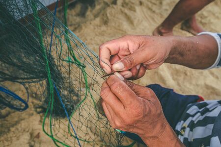 Selective focus on fisherman's hand, repairing fishing netの写真素材