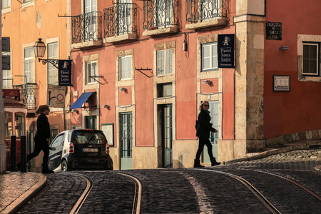 LISBON, PORTUGAL - DECEMBER 27 2015: An old tradition residents building facade with tram railway in the old Alfama quarter in Lisbon, Portugal. People crossing the streetのeditorial素材