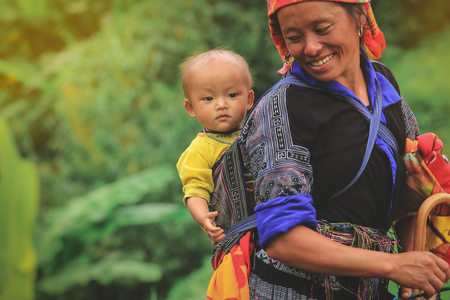 Mu cang chai, Vietnam-August 27, 2018: Smling Hmong tribe woman carrying her child in her backpack...