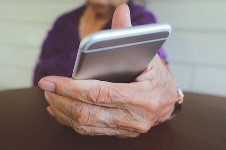 Hands of an elderly woman holding a mobile phoneの写真素材