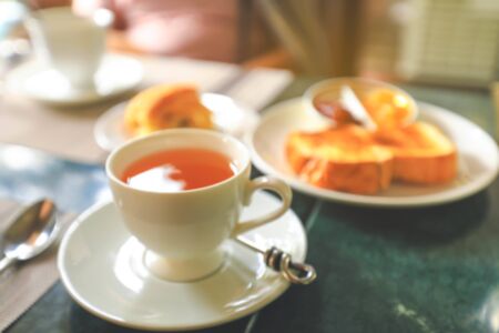 Blurred image of a cup of hot tea  and toasts on tableの写真素材