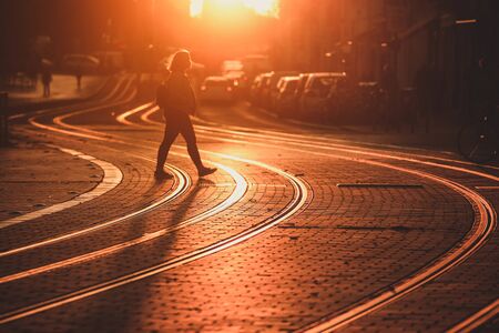 Street photography, selective focus on Tram rail with  blurred woman walking on tram railway during the sunset in Bordeaux city, France.の写真素材
